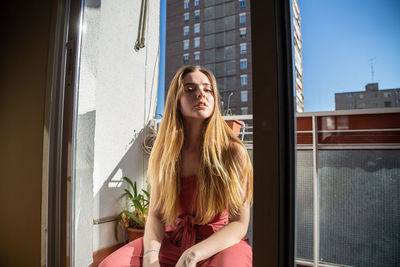 Young woman looking through window