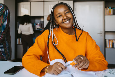 Portrait of smiling young woman with braided hair sitting at university