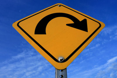 Low angle view of road sign against blue sky