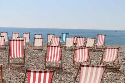 Chairs on beach against clear sky