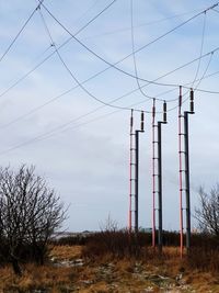 Low angle view of electricity pylon on field against sky