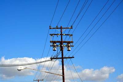 Low angle view of electric pole against blue sky