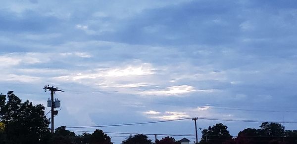 Low angle view of silhouette electricity pylon against sky