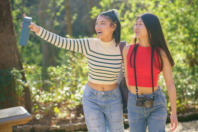 Portrait of young woman standing against plants