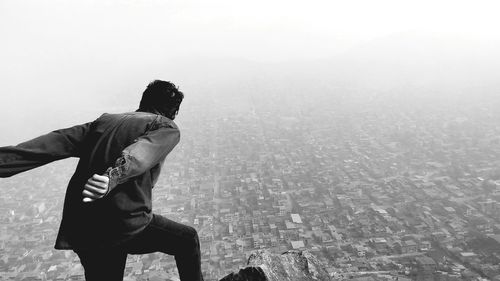 Man on rock formation in foggy weather