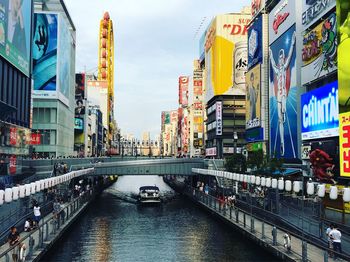 Bridge over river amidst buildings in city against sky