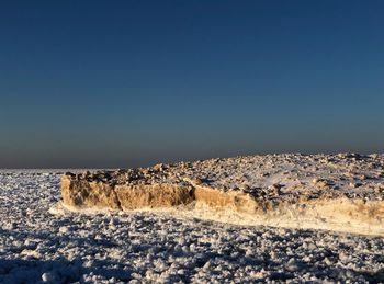 Scenic view of land against clear blue sky during winter