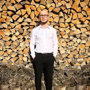 Portrait of man wearing eyeglasses standing against firewood