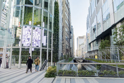 People walking on modern glass building in city