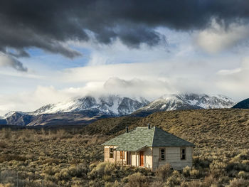 House on mountain against cloudy sky