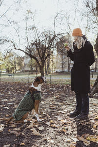 Full length of young woman playing ball with boxer dog at park