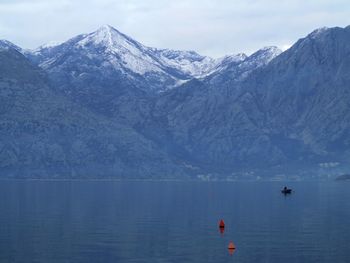 Scenic view of sea and snowcapped mountains against sky