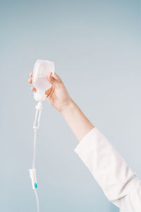 Midsection of person holding bottle against white background