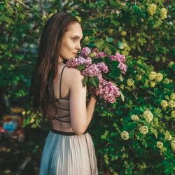 Beautiful young woman standing by flowering plants