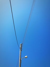 Low angle view of power lines against clear blue sky