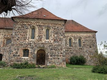 Old building by trees against sky