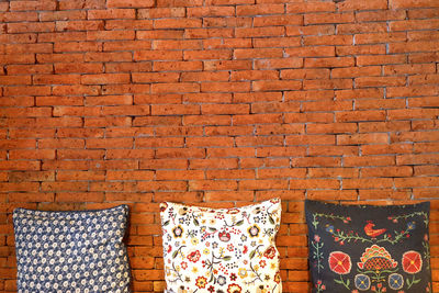 Three pillows with brick background have space for idea