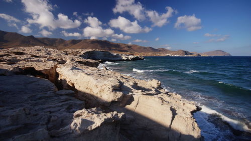 Rock formations at sea shore against sky