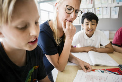 Teacher and students reading from book in classroom