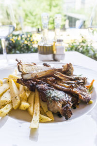 Close-up of lamb chops with french fries served in plate on table