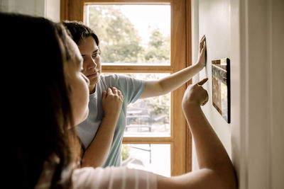 Mother and daughter using home automation through digital tablet mounted on wall at home