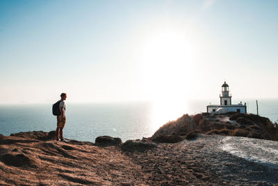 Man standing on lighthouse by sea against clear sky