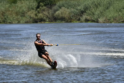Full length of man slalom water skiing on river