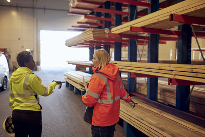 Rear view of multiracial female colleagues discussing while walking in lumber industry