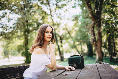 Portrait of young woman sitting at table in park