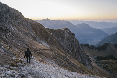 Rear view of woman walking on mountain ridge