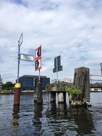 Flag on wooden post on river spree in berlin against sky