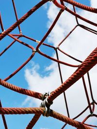 Low angle view of rusty fence against sky