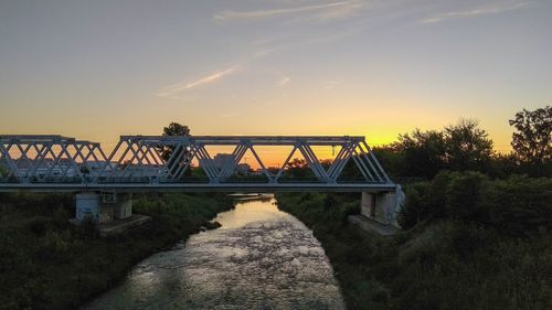 Bridge over river against sky during sunset