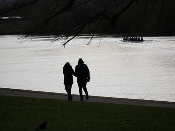 Silhouette of couple walking by the river trent in nottingham. rowing boat in the distance.