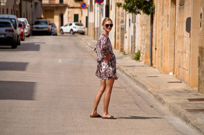 Full length portrait of young woman on street in city