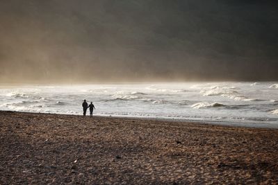 People standing on beach against sky