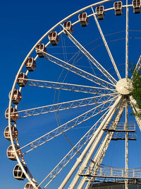 Low angle view of ferris wheel against clear blue sky