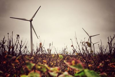 Wind turbines on field against sky