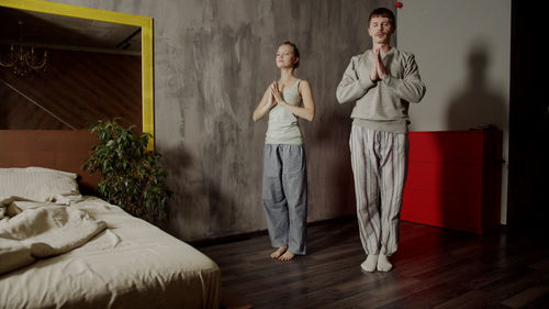 Portrait of young woman standing on bed at home