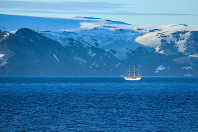 Scenic view of sea and snowcapped mountains against sky