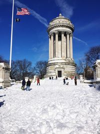 American flag by soldiers and sailors monument on snow covered field against sky