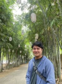 Portrait of young man standing against trees