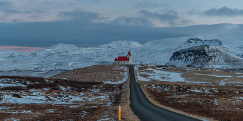 Full frame view of a road to a church on hill with snow covered mountains in background near sunset