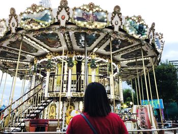 Rear view of woman at amusement park against sky