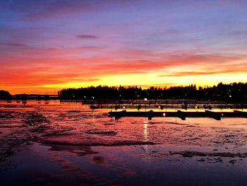 Silhouette boats in lake against orange sky