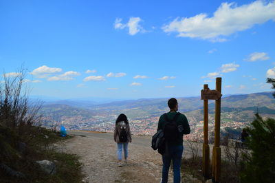 Rear view of people standing on mountain against sky