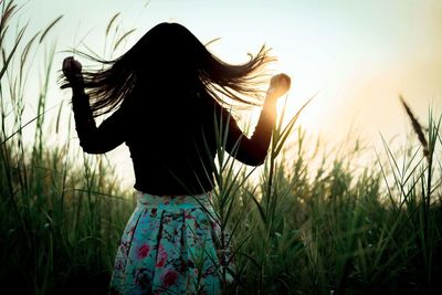 Rear view of silhouette woman on field against sky