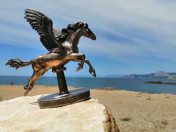 Statue horse on beach against sky