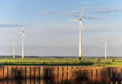 Wind turbines on field against sky