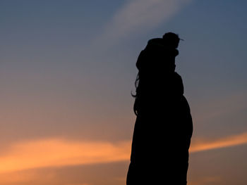 Silhouette woman standing against orange sky